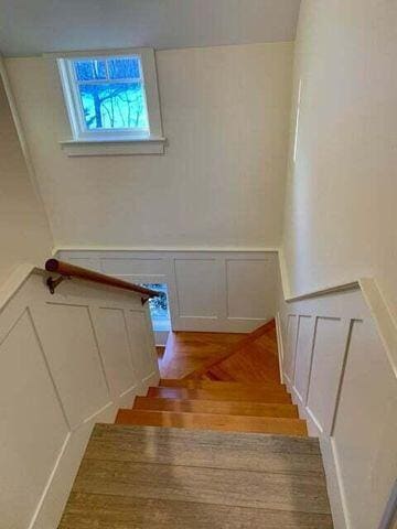 staircase featuring a wainscoted wall, a decorative wall, and wood finished floors