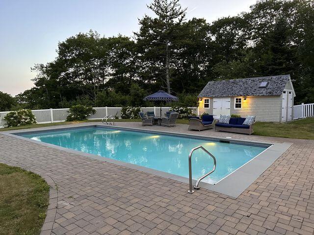 view of swimming pool with an outbuilding, outdoor lounge area, fence, a fenced in pool, and a patio area