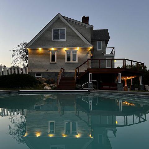 rear view of house with stairs, a chimney, an outdoor pool, and a wooden deck