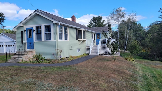 view of front of house with a chimney, roof with shingles, a front yard, and an outdoor structure