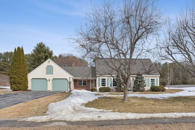 cape cod house featuring aphalt driveway, an attached garage, and a chimney