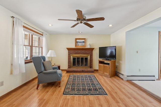 living area featuring recessed lighting, light wood-type flooring, baseboard heating, and a brick fireplace