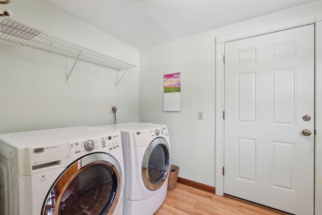 clothes washing area featuring baseboards, separate washer and dryer, laundry area, and light wood finished floors