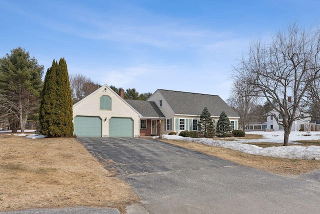 view of front facade featuring a garage, a chimney, and driveway