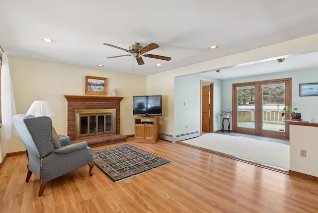 living area featuring ceiling fan, recessed lighting, light wood-style flooring, a fireplace, and a baseboard radiator