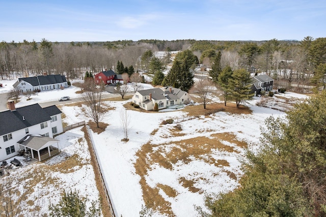 snowy aerial view featuring a wooded view