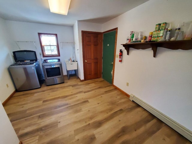 interior space featuring a baseboard heating unit, a kitchen breakfast bar, baseboards, independent washer and dryer, and light wood finished floors