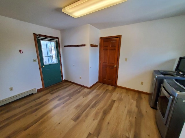 laundry room with light wood finished floors, baseboard heating, separate washer and dryer, laundry area, and baseboards