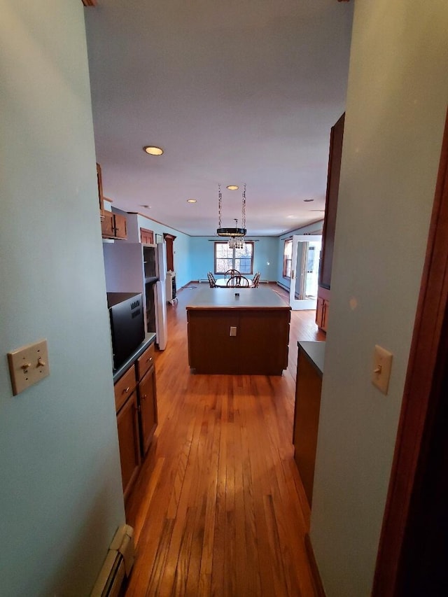 kitchen with light wood-style flooring, brown cabinets, open floor plan, a center island, and light countertops