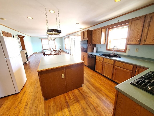 kitchen with black dishwasher, wall oven, freestanding refrigerator, a kitchen island, and a sink