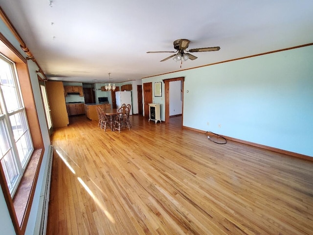 unfurnished living room featuring light wood-style floors, a baseboard heating unit, ornamental molding, and baseboards