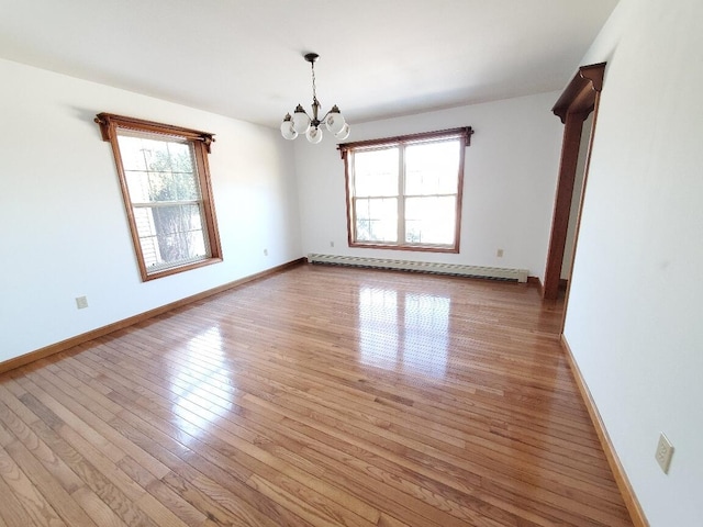 empty room featuring a chandelier, baseboards, light wood finished floors, and baseboard heating