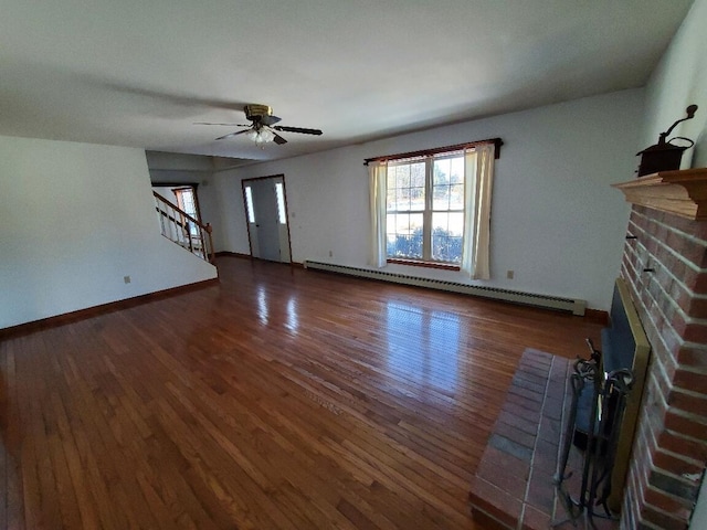 unfurnished living room featuring ceiling fan, a baseboard radiator, stairs, a brick fireplace, and dark wood-style floors