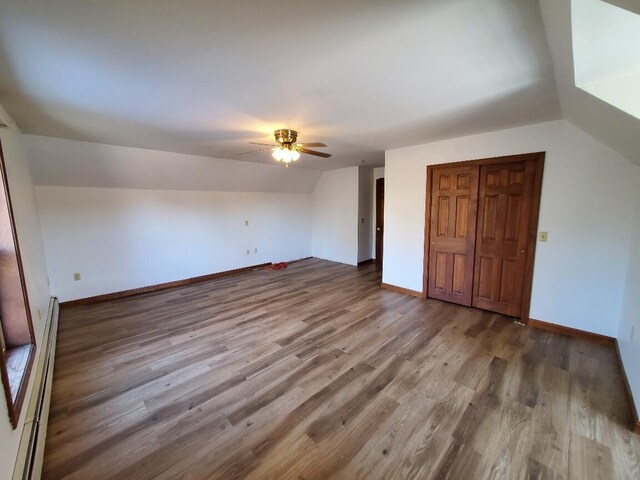 additional living space with baseboards, ceiling fan, a baseboard radiator, wood finished floors, and vaulted ceiling