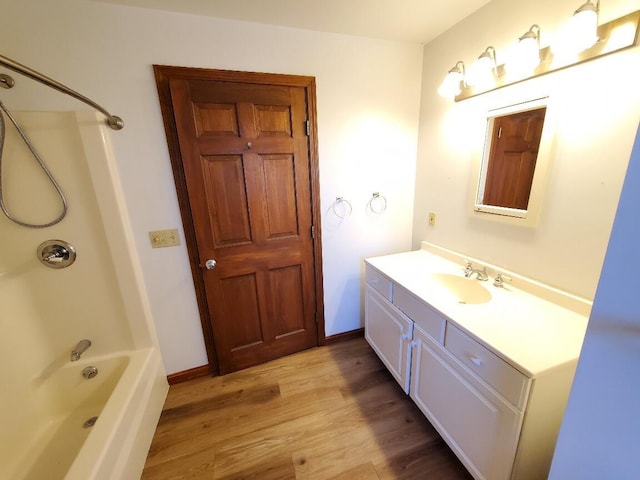 bathroom featuring shower / tub combination, wood finished floors, vanity, and baseboards