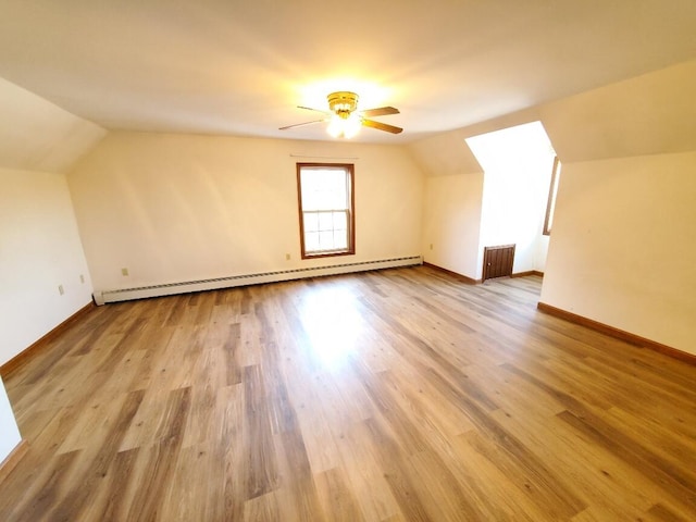 additional living space with lofted ceiling, light wood-style floors, baseboards, and baseboard heating