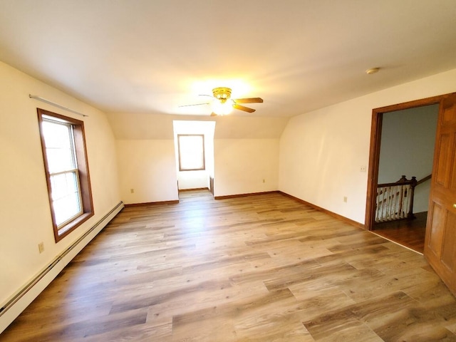 bonus room with a baseboard radiator, lofted ceiling, a ceiling fan, wood finished floors, and baseboards