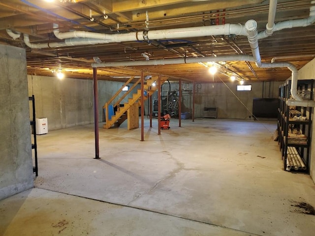 unfinished basement featuring stairway and heating fuel