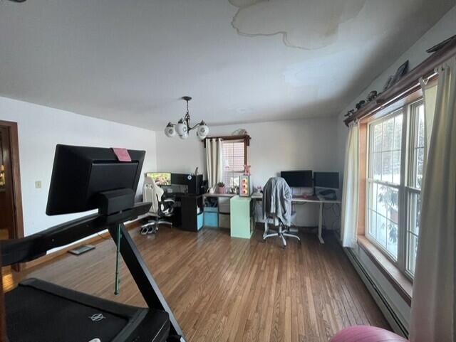 exercise room featuring a notable chandelier, baseboard heating, and wood finished floors