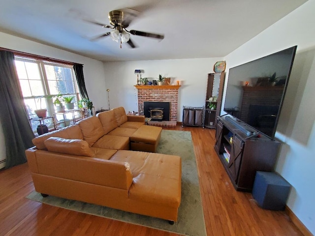 living area with ceiling fan, a fireplace, and wood finished floors