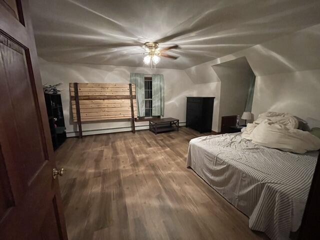 bedroom featuring a baseboard heating unit and wood finished floors