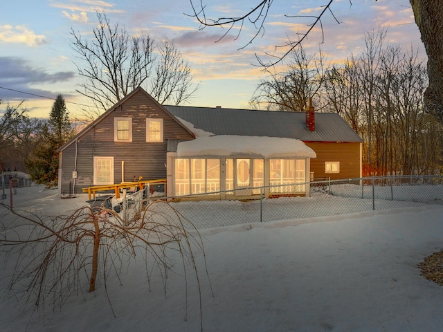 back of house with a chimney, a sunroom, and fence