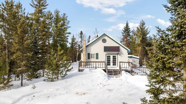 snow covered house with a chimney and a wooden deck