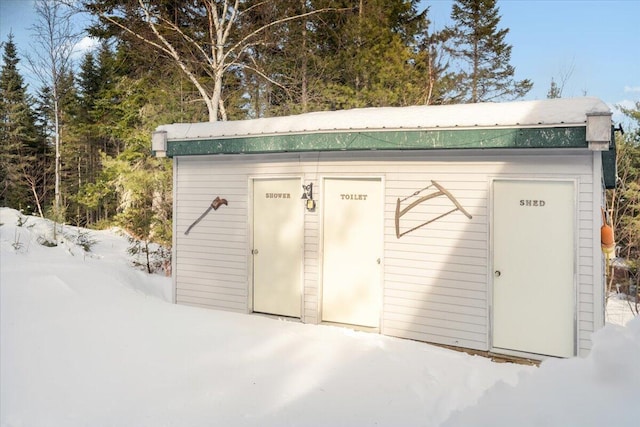 snow covered structure with an outbuilding