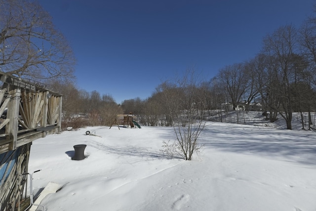 snowy yard featuring a playground