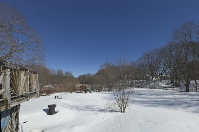 snowy yard featuring a playground