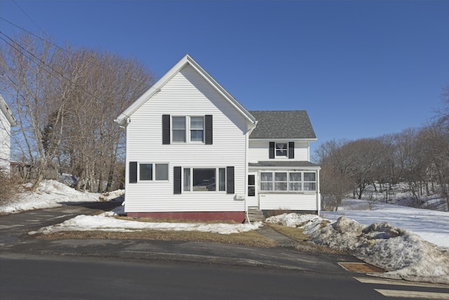 traditional-style home featuring a shingled roof, entry steps, and a sunroom