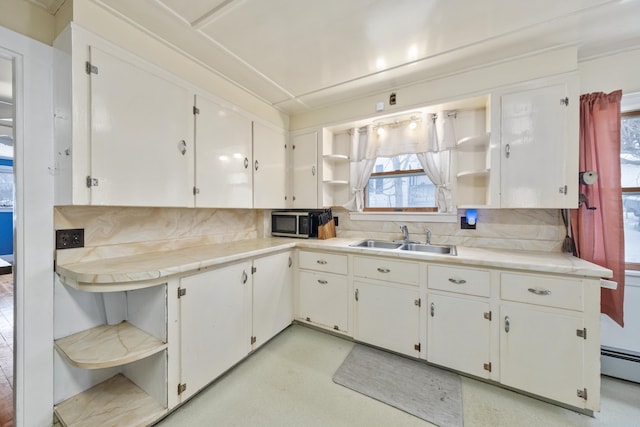 kitchen with open shelves, stainless steel microwave, backsplash, white cabinets, and a sink