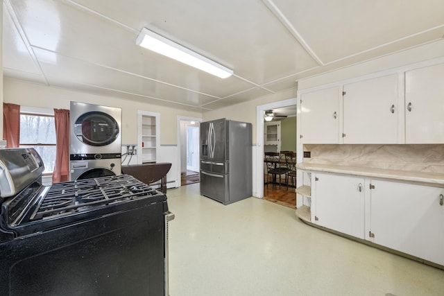 kitchen featuring stacked washer and dryer, white cabinetry, light countertops, appliances with stainless steel finishes, and decorative backsplash