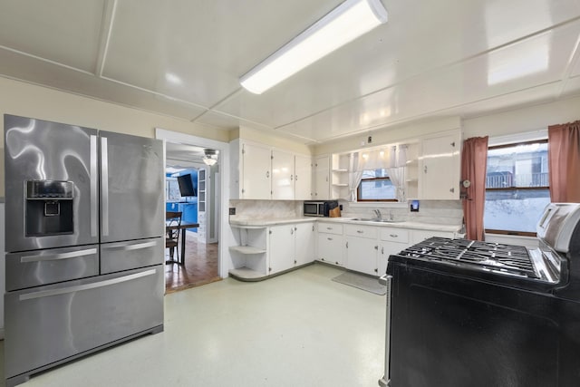 kitchen with a sink, white cabinets, light countertops, appliances with stainless steel finishes, and open shelves