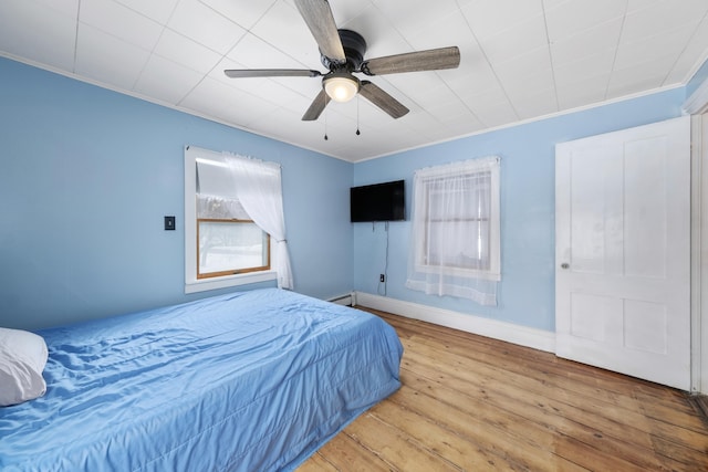 bedroom featuring ceiling fan, ornamental molding, wood finished floors, and baseboards