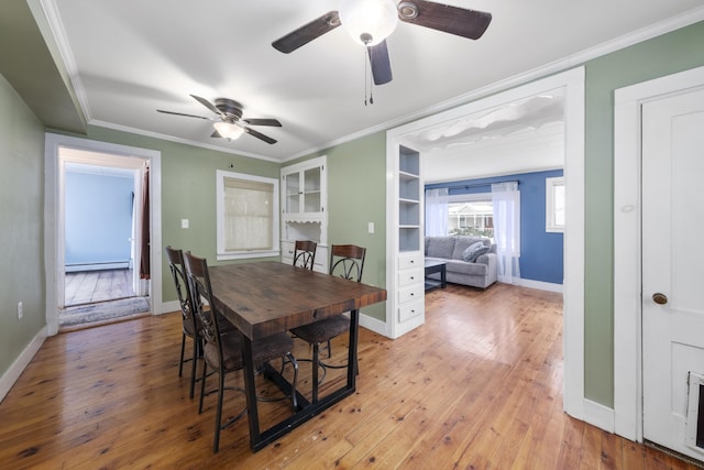 dining area with a baseboard radiator, ornamental molding, light wood-style flooring, and baseboards