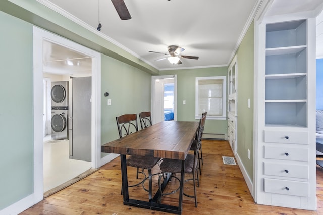 dining space with ornamental molding, stacked washer and clothes dryer, visible vents, and light wood-style flooring