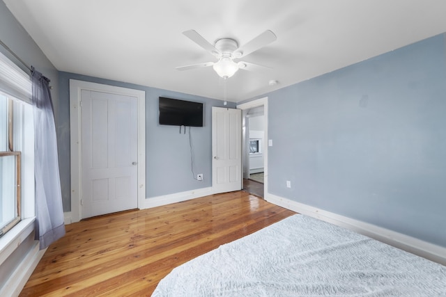 bedroom with baseboards, multiple windows, a ceiling fan, and light wood-style floors