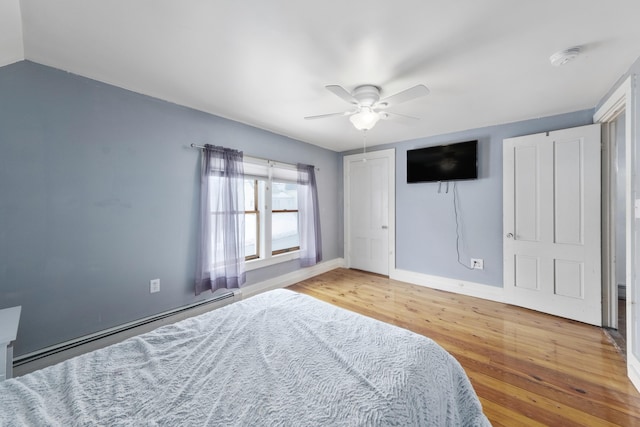 bedroom featuring a baseboard heating unit, a ceiling fan, vaulted ceiling, wood finished floors, and baseboards