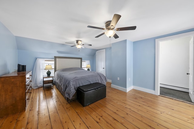 bedroom with a baseboard heating unit, a ceiling fan, baseboards, vaulted ceiling, and wood-type flooring