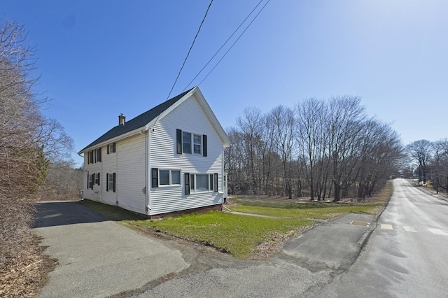 view of side of property featuring aphalt driveway and a lawn