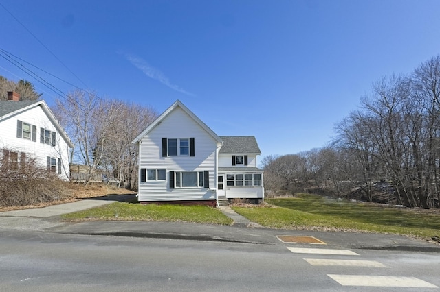 traditional-style home featuring a shingled roof and a front yard