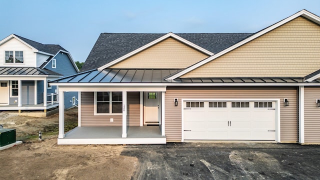 view of front of property with a porch, a standing seam roof, driveway, and an attached garage