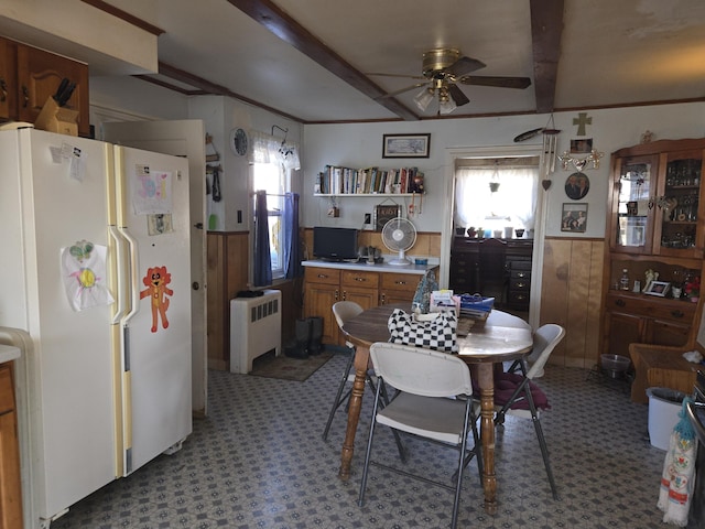 dining space with a wainscoted wall, wood walls, and radiator heating unit