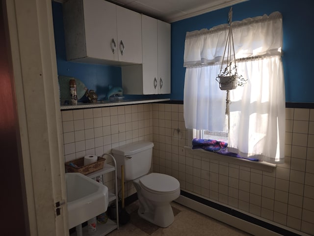 half bath featuring a baseboard heating unit, a wealth of natural light, toilet, and tile walls