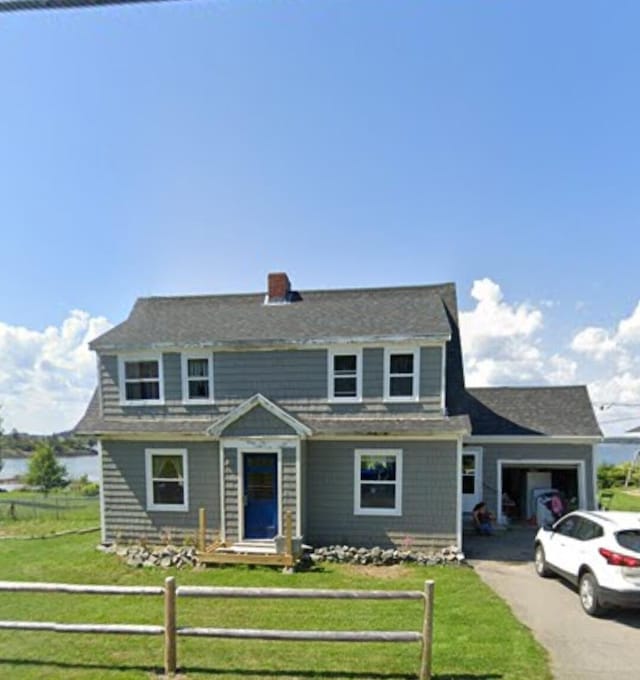 view of front of house featuring aphalt driveway, a fenced front yard, an attached garage, a front lawn, and a chimney