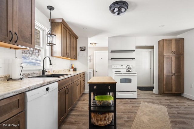 kitchen featuring dark wood-style floors, decorative light fixtures, a sink, light stone countertops, and white appliances