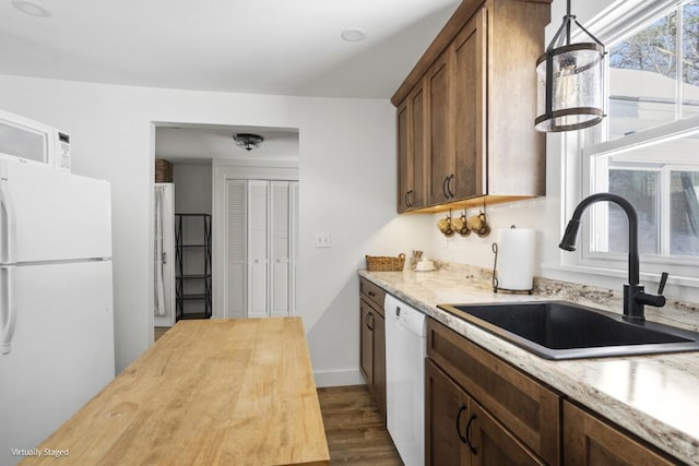 kitchen featuring dark wood-type flooring, a sink, wood counters, white appliances, and baseboards