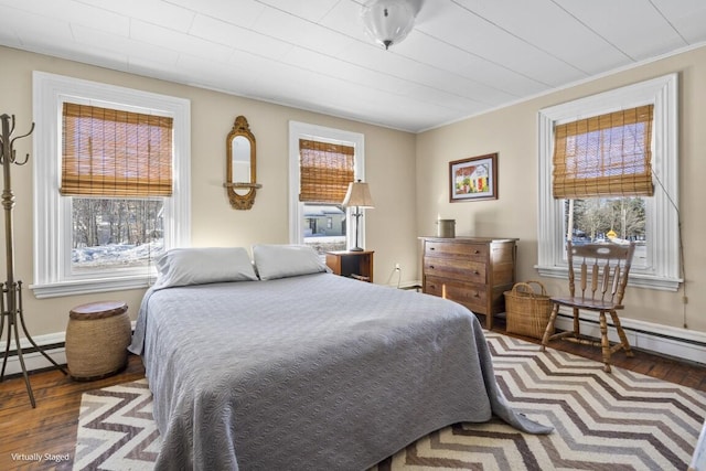 bedroom featuring a baseboard heating unit, dark wood-type flooring, and baseboards