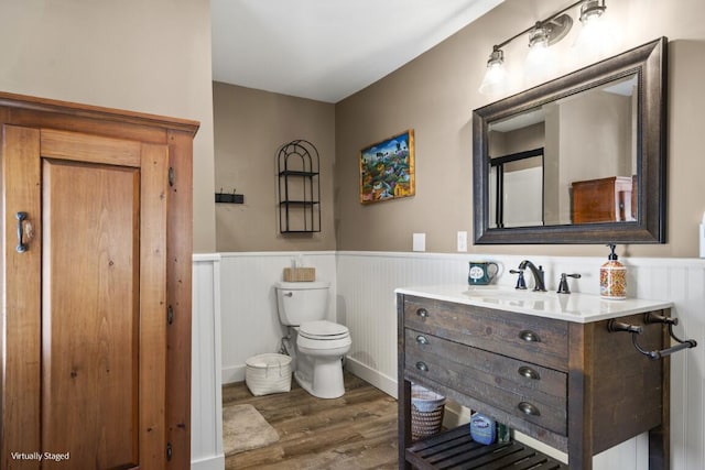 bathroom featuring toilet, a wainscoted wall, wood finished floors, and vanity